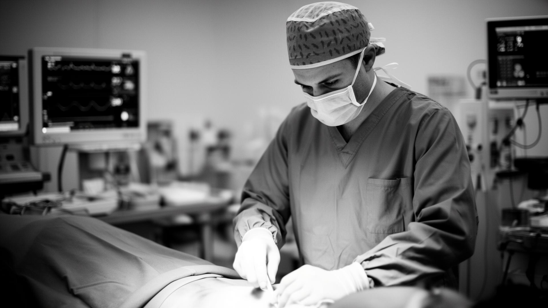 Clinician in scrubs and mask attending to a patient in an operating room
